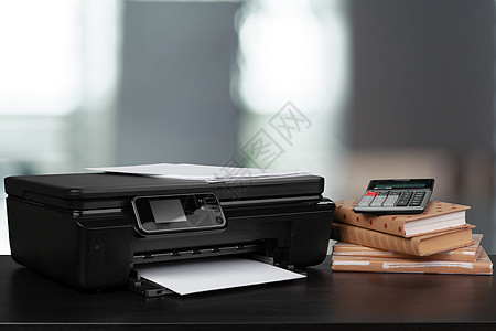 在模糊背景下堆放书本和家用打印机黑色办公室职场桌子文书扫描器文档墨水复印件电子产品图片