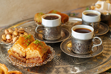 传统的阿拉伯甜甜点肉汁 加一杯咖啡土豆咖啡桌子食物金属蜂蜜火鸡咖啡店坚果午餐托盘咖啡杯图片