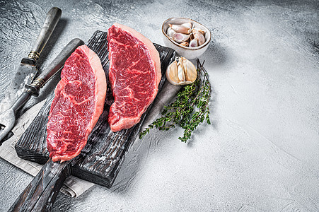 木板上配有肉刀和叉子的生牛肉肉牛排 白色背景 顶端视图图片