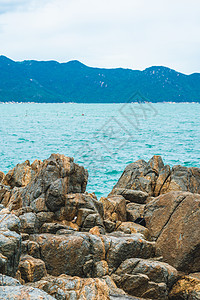 垂直视图破旧的悬崖积云云天空山岛背景纯蓝色 lazure 空海天际线 灰色棕色石头岩石纹理生动的颜色 大流行后的概念旅游 自然的图片