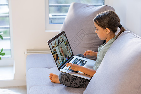 学龄的小女孩正在家里学习 一个女孩在笔记本电脑显示器上观看视频课程 并在笔记本上写任务女士桌子孩子知识大学青少年老师学生瞳孔互联图片