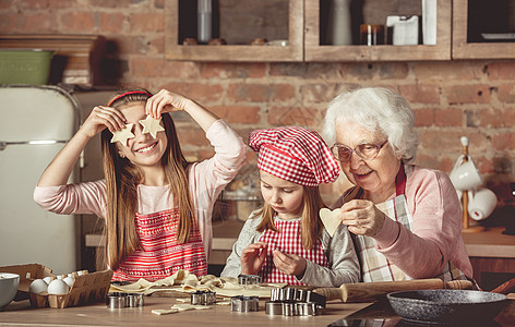 外婆教孙女烤饼干的孩子桌子烹饪乐趣闲暇微笑祖母孙子女孩帮助图片