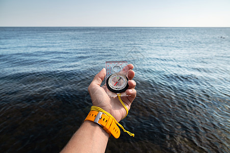 手握手腕手表手镯的人 在海面背景下拿着磁罗盘的铁手图片