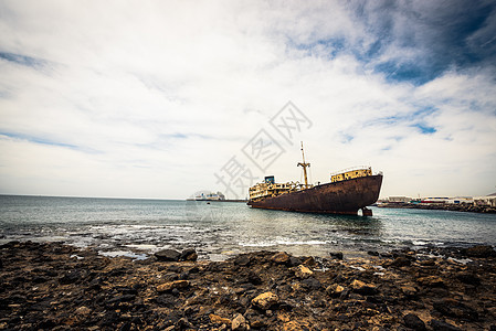 兰萨罗特海岸附近被破解的船支撑腐蚀衰变石头蓝色损害海滩天空废墟海岸图片