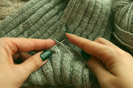 编织     年轻女性用编织针头和灰色羊毛卷的手纺织品针线活环形手工爱好棉布围巾手工业衣服时尚图片