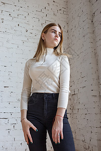 穿着白色毛衣和黑色牛仔裤的年轻有思想的青少年模特肖像阁楼女性青年头发模型魅力试验金发女郎造型工作室图片