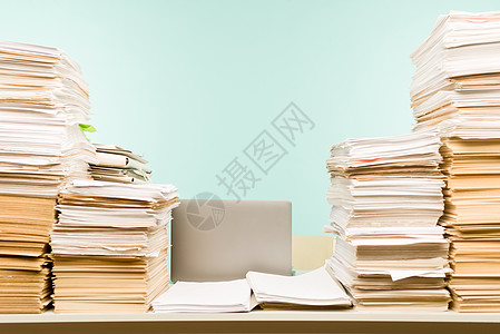 在办公室的桌面上堆放纸研究报告文件夹文书工作记录文学账单电脑档案图片