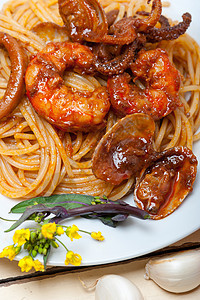 意大利海鲜意大利面配红番茄酱香菜乡村木头午餐甲壳桌子美食面条鱿鱼餐厅图片