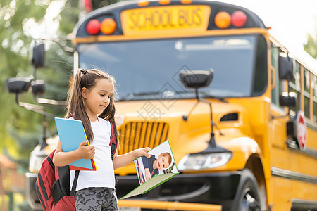 带着背包站在巴士旁边的可爱女孩去学校 装扮成摄像头近身童年青年姿势知识运输教育公共汽车女学生车辆瞳孔图片