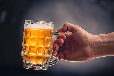 握着啤酒杯的手酒精黄色玻璃金子工艺液体泡沫气泡酒吧灰色图片
