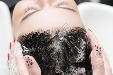 美发师用洗发水洗黑发女人的长发图片