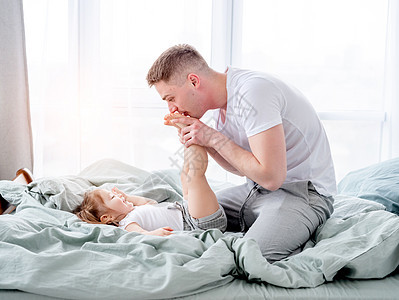 父亲和女儿在床上男性卧室拥抱女性毯子乐趣快乐童年微笑女孩图片