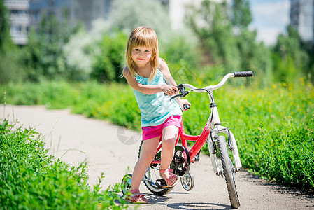 在公园里骑自行车的可爱小女孩青年活动幸福闲暇女孩孩子健康运动娱乐乐趣图片