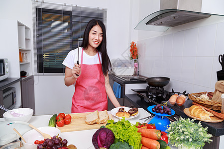 在厨房里拿着刀子的女人女孩桌子木头食物手指厨师烹饪食谱饮食家庭背景图片