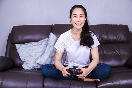 在客厅沙发上玩电玩游戏的女用操控器技术女士控制器喜悦玩家安慰电子游戏乐趣电脑爱好图片