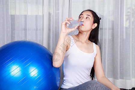 妇女锻炼健身球后饮用水的饮用量窗户生活训练瑜伽身体平衡运动百叶窗蓝色瓶子图片