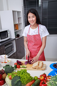 在厨房房里切紫色卷心菜的女人蔬菜烹饪女性食物沙拉房子胡椒饮食微笑围裙图片