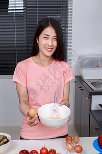 妇女烹饪和在厨房的碗里煮鸡蛋食物成人平底锅水果鞭打桌子厨师柜台烘烤玻璃图片