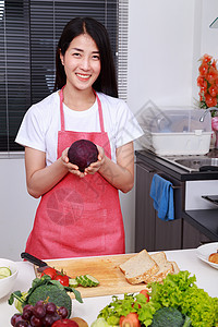 幸福的女子在厨房房间拿着紫色卷心菜胡椒沙拉蔬菜食物围裙营养女性房子微笑饮食图片