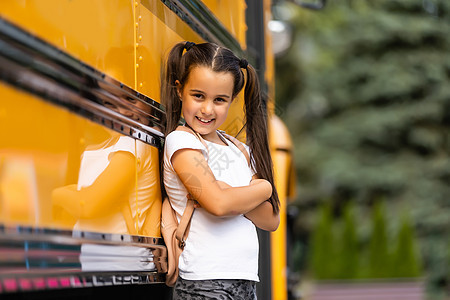 带着背包站在巴士旁边的可爱女孩去学校 装扮成摄像头近身青年学习头发姿势公共汽车瞳孔小学生青少年孩子运输图片