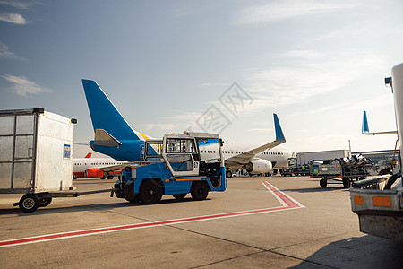 在大现代飞机附近的机场拖拉机 白天在机场枢纽准备飞机图片