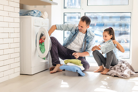 幸福家庭在家将衣物装入洗衣机中父母父亲家务孩子微笑生活洗衣店房子女性亲子图片