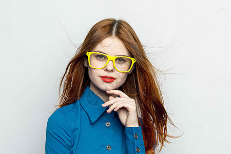 穿蓝色衬衫 穿着黄色眼镜的女商务人士商业头发相机桌子白色红色工作室女孩灰色女士图片