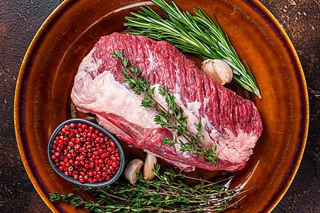 生牛肉肉 烧在有草药的生锈盘子上 深色背景牛扒胸部鱼片食物迷迭香烧烤圆形红色大理石纹臀部图片