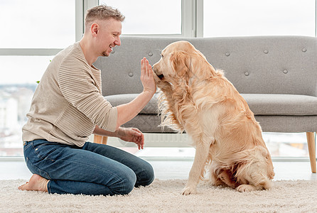 男人和金色猎犬坐在一起忠诚成人晴天爪子宠物动物微笑幸福男性友谊图片