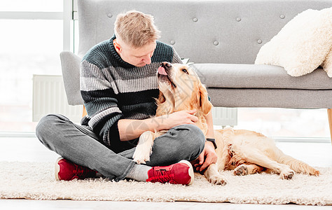 男人和金色猎犬坐在一起摄影友谊阳光拥抱晴天幸福动物乐趣朋友微笑图片