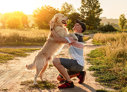 站在人旁边的金色寻金者哺乳动物火车猎犬宠物男性训练友谊动物旅行日落图片