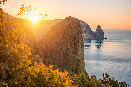 与温暖的日落光的秋天海风景在岩石海岸线 在多岩石的海岸背景下平静的海面 秋季旅行和休息的完美场所的概念图片