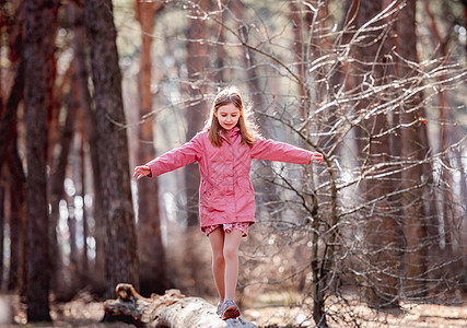 小女孩在木柴中行走孩子粉色微笑日志木头森林头发外套公园幸福图片