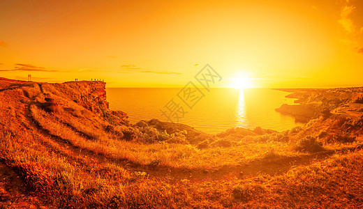 全景海景 岩石海岸景观 平静的蔚蓝大海和红色燃烧的日落 复制空间 复制空间 美丽世界 自然和户外旅行的概念图片