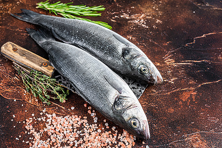 海盆或海贝斯鱼 在含盐和草药 深色背景的刀子上的新鲜生鱼图片