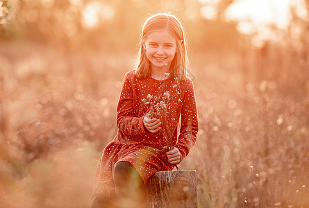 在户外有秋花的小女孩娘娘腔阳光褪色橙子季节公园孩子木头女孩森林图片