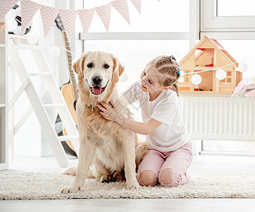 快乐的小女孩抱着美丽的狗友谊游戏室微笑小学生宠物房间动物幸福公寓孩子图片