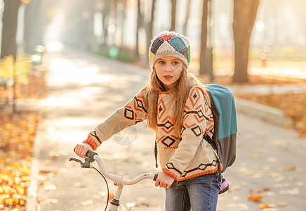 骑自行车上学的女孩季节女学生快乐学校环境叶子微笑金子背包孩子图片