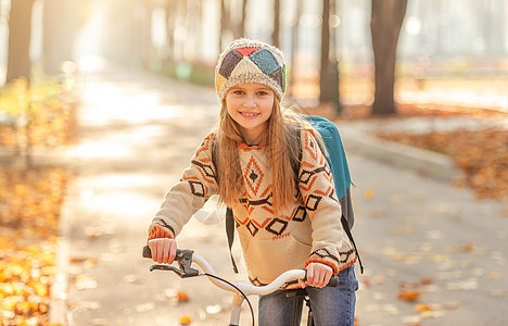 骑自行车上学的女孩季节树木树叶微笑叶子环境背包金子学校快乐图片