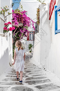 小女孩走在希腊狭窄的小巷子上旅行太阳粉饰石头窗户蓝色建筑学街道脚步花朵图片