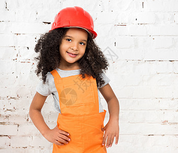 穿橙色修理工制服的小女孩粉饰工作室肤色工人女孩深色头盔红色照片孩子图片
