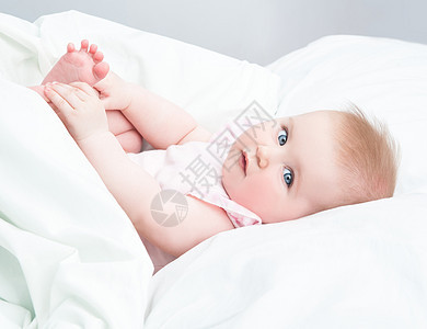 婴儿用脚玩耍眼睛童年孩子幸福孩子们卧室金发快乐女孩毯子图片