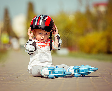 婴儿户外穿着溜冰鞋和头盔的2岁女孩活动孩子乐趣童年溜冰者运动幸福享受滚筒森林背景