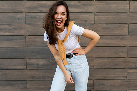 情绪积极快乐快乐漂亮的年轻黑发女人穿着时髦的衣服的照片 美丽迷人的女性站在街外 表现出真挚的情感生活潮人乐趣情怀微笑球衣喜悦城市图片