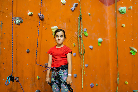 运动的小女孩在健身房的实际墙壁上爬人造巨石爱好闲暇操场娱乐绳索岩石女孩假期行动挑战图片