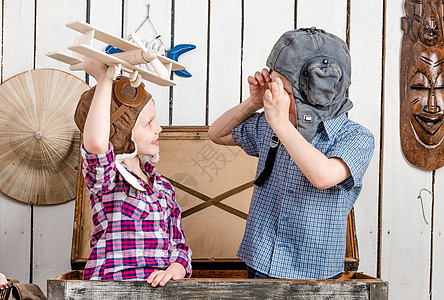 拿着木制飞机的小女孩和戴驾驶帽的男孩帽子航班冒险游客胸部工作室相机孩子们男生房间图片