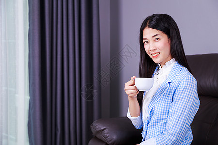 拥有咖啡或茶杯的快乐女商务人士人士办公室管理人员女性窗户沙发女士工作经理饮料图片