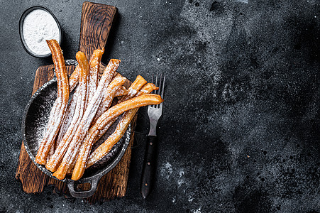 墨西哥传统甜甜点 churros 带糖粉在锅中 黑色背景 顶视图 复制空间乡村棕色街道粉末白色面包甜点早餐美食小吃图片