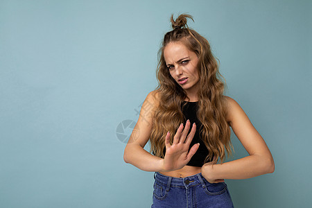 年轻的悲伤让美丽迷人的金发卷发女人心烦意乱 她带着真诚的情感 穿着时尚的黑色上衣 与蓝色背景隔离 有复制空间 没有任何手势图片