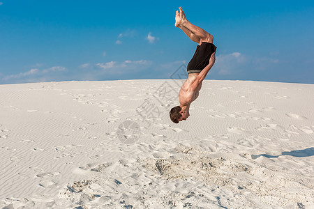 年轻公园男的肖像 在沙滩上做翻转或摩擦运动男性太阳空翻体操喜悦蓝色自由青年航班图片